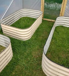 Assembled raised beds inside garden polytunnel installation.